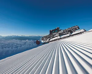 Skidbacke, snö, blå himmel, pistmaskin